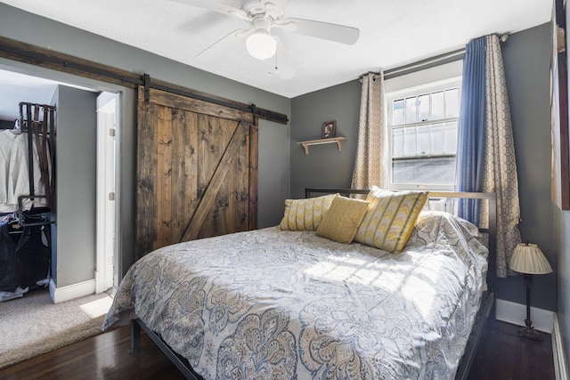 bedroom with a barn door, dark wood-type flooring, and ceiling fan