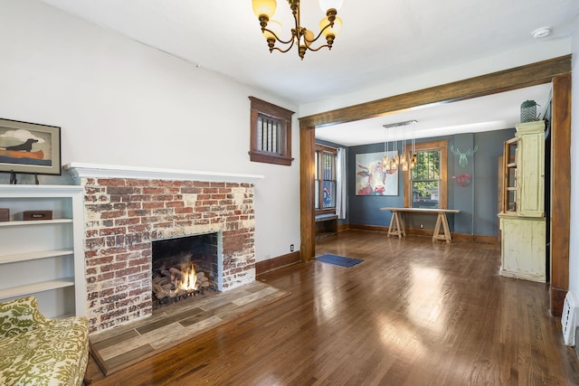 unfurnished living room featuring dark hardwood / wood-style flooring, a notable chandelier, a brick fireplace, and baseboard heating