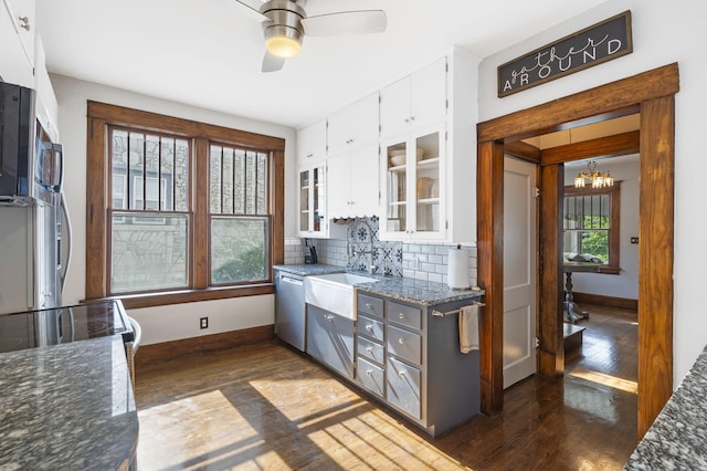 kitchen with dishwasher, dark hardwood / wood-style floors, white cabinets, decorative backsplash, and dark stone counters