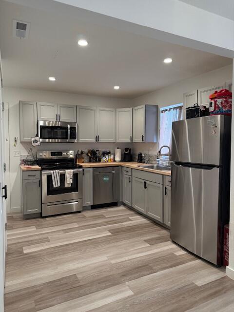 kitchen featuring gray cabinets, appliances with stainless steel finishes, sink, and light hardwood / wood-style flooring