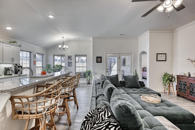 living room featuring crown molding, light hardwood / wood-style flooring, a healthy amount of sunlight, and vaulted ceiling