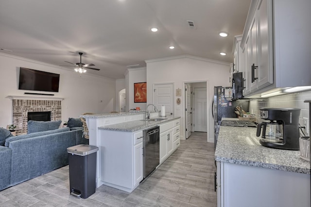 kitchen featuring dishwashing machine, sink, white cabinetry, backsplash, and light stone counters