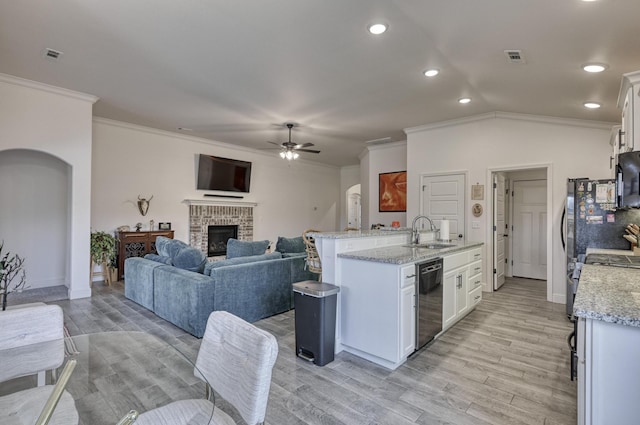 kitchen with white cabinetry, black dishwasher, sink, light stone countertops, and light wood-type flooring