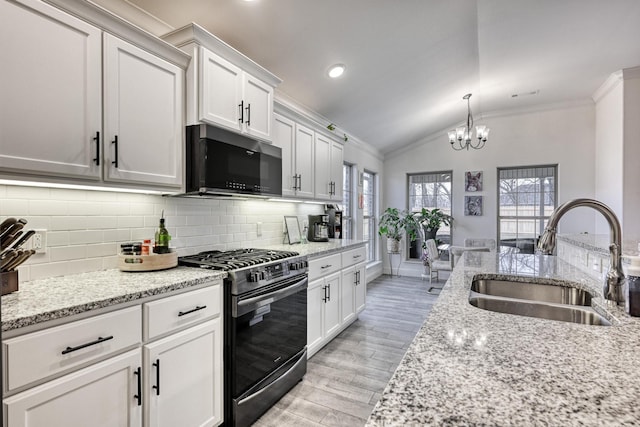 kitchen with sink, gas range, vaulted ceiling, and white cabinets