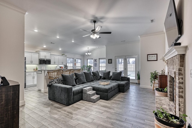 living room featuring a fireplace, ceiling fan with notable chandelier, light hardwood / wood-style flooring, and ornamental molding