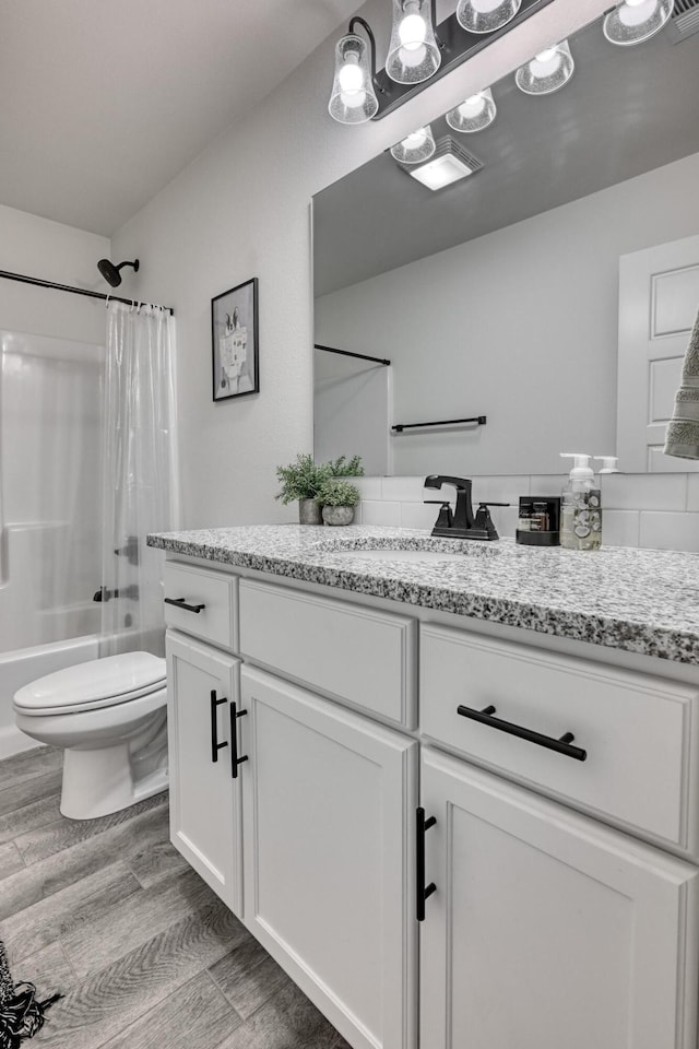 full bathroom featuring hardwood / wood-style flooring, vanity, shower / tub combo with curtain, and toilet