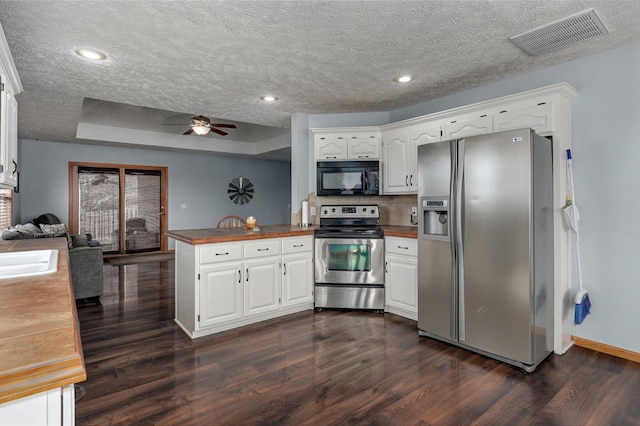 kitchen featuring dark hardwood / wood-style floors, stainless steel appliances, kitchen peninsula, and white cabinets