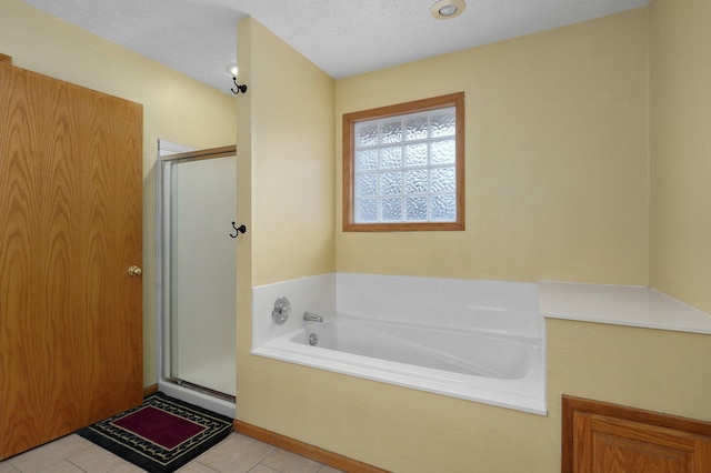 bathroom with tile patterned flooring, shower with separate bathtub, and a textured ceiling