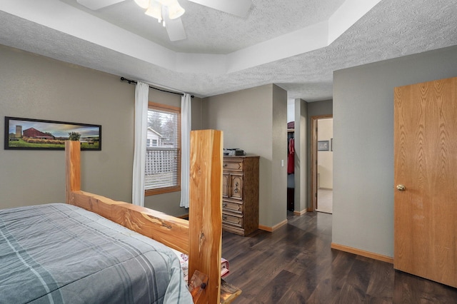 bedroom featuring dark wood-type flooring, ceiling fan, a raised ceiling, and a textured ceiling