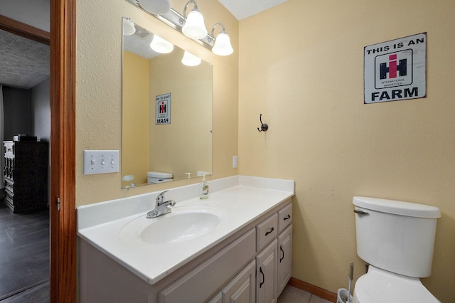 bathroom with vanity, toilet, and a textured ceiling