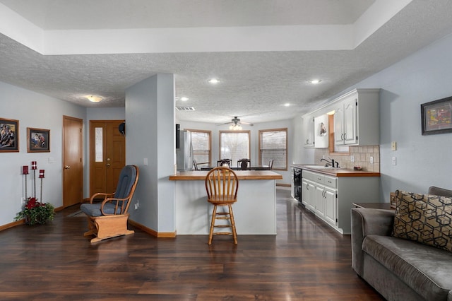 kitchen featuring white cabinetry, sink, a breakfast bar area, decorative backsplash, and kitchen peninsula