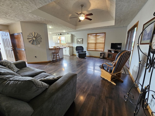 living room with a textured ceiling, dark wood-style flooring, and baseboards