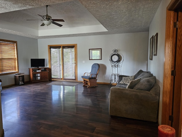 living room featuring a ceiling fan, a raised ceiling, a textured ceiling, and wood finished floors