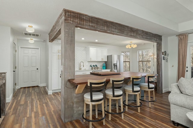 kitchen with wood counters, white cabinetry, sink, stainless steel fridge with ice dispenser, and dark wood-type flooring