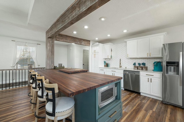 kitchen featuring a kitchen island, wood counters, tasteful backsplash, white cabinets, and stainless steel appliances