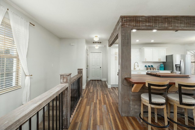 bar featuring sink, white cabinetry, dark hardwood / wood-style floors, stainless steel refrigerator with ice dispenser, and tasteful backsplash