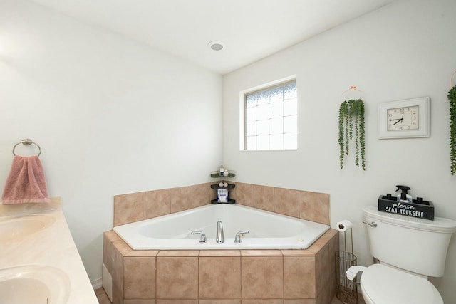 bathroom with a relaxing tiled tub, vanity, and toilet