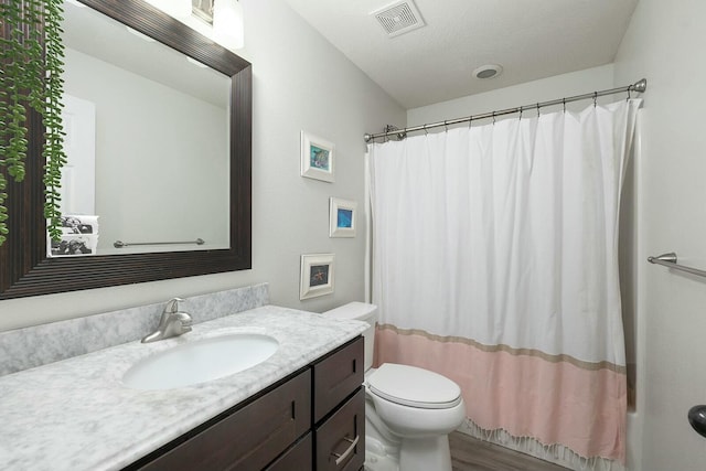 full bathroom with shower / bath combo, hardwood / wood-style floors, vanity, a textured ceiling, and toilet