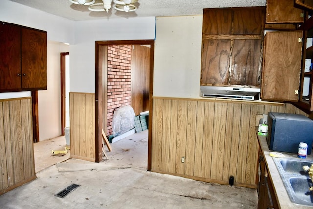 kitchen with sink, a textured ceiling, and wood walls