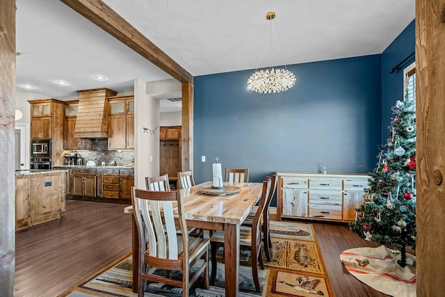 dining space featuring dark wood-type flooring, a chandelier, and beam ceiling