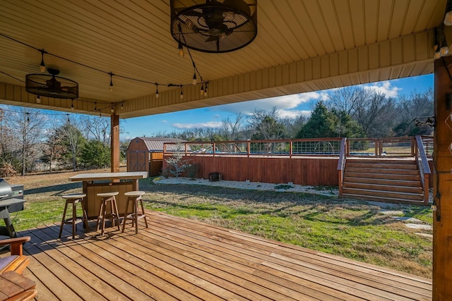 wooden terrace featuring ceiling fan and a shed