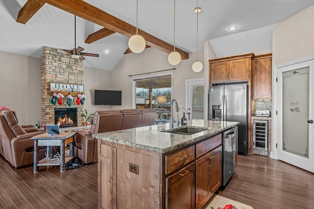 kitchen featuring sink, light stone counters, pendant lighting, beverage cooler, and a kitchen island with sink