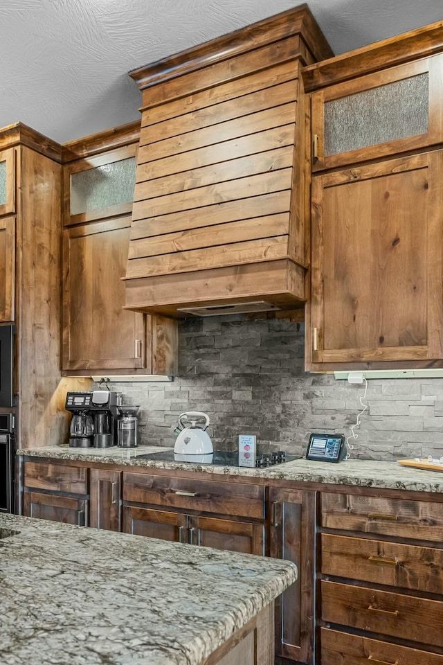 kitchen featuring tasteful backsplash, stainless steel oven, and light stone counters