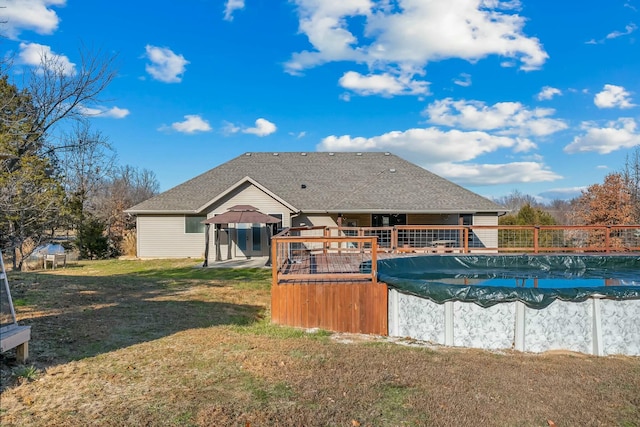 rear view of house with a gazebo, a covered pool, and a lawn