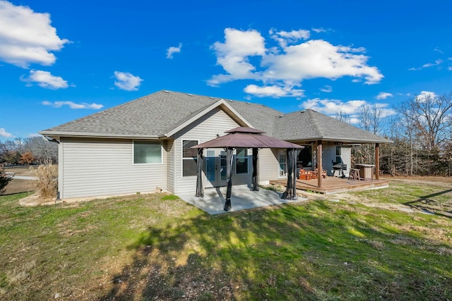 rear view of property with a wooden deck, a gazebo, a lawn, and a patio