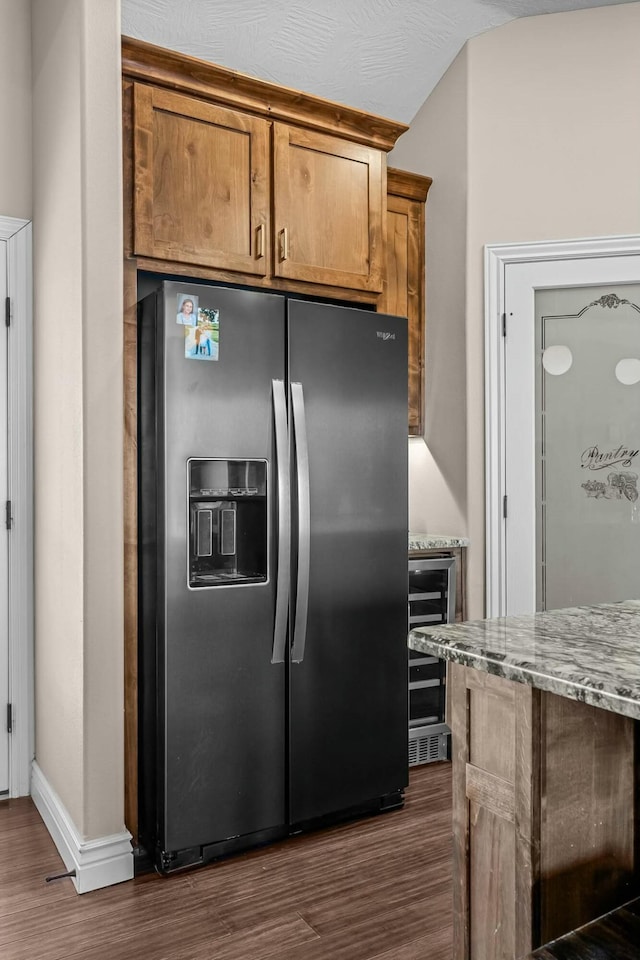 kitchen with dark hardwood / wood-style flooring, stainless steel fridge with ice dispenser, light stone countertops, and beverage cooler