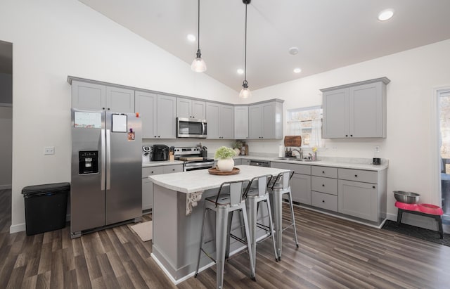 kitchen featuring a breakfast bar, pendant lighting, high vaulted ceiling, a center island, and stainless steel appliances