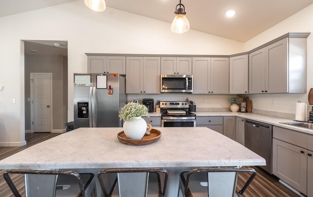 kitchen with hanging light fixtures, vaulted ceiling, stainless steel appliances, and a kitchen island