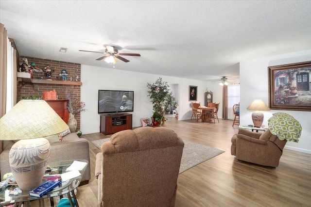 living room with hardwood / wood-style flooring, ceiling fan, and a textured ceiling