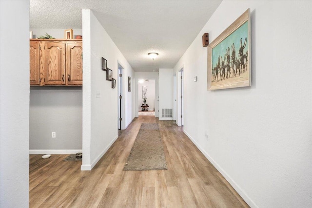 hall featuring light hardwood / wood-style floors and a textured ceiling