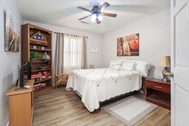 bedroom featuring hardwood / wood-style flooring, a textured ceiling, and ceiling fan