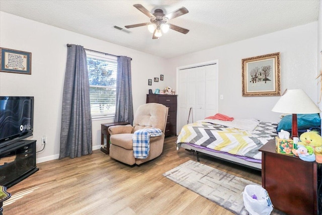 bedroom featuring a textured ceiling, a closet, ceiling fan, and light wood-type flooring