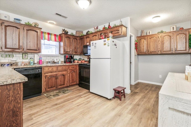 kitchen with backsplash, a textured ceiling, light hardwood / wood-style flooring, and black appliances