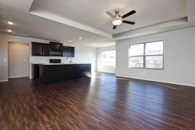 unfurnished living room with sink, dark wood-type flooring, ceiling fan, a textured ceiling, and a raised ceiling