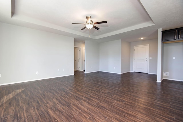 spare room with ceiling fan, a tray ceiling, and dark hardwood / wood-style flooring