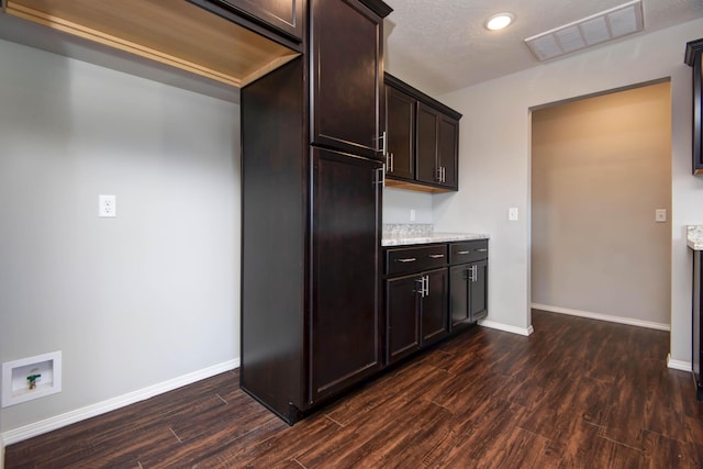 kitchen featuring light stone counters, dark hardwood / wood-style floors, and dark brown cabinets