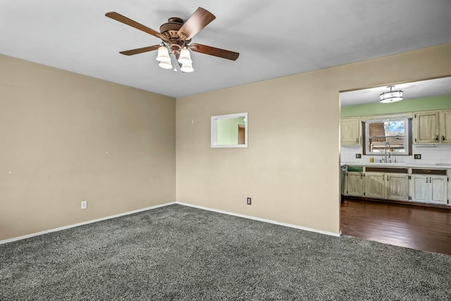 spare room with ceiling fan, sink, and dark carpet