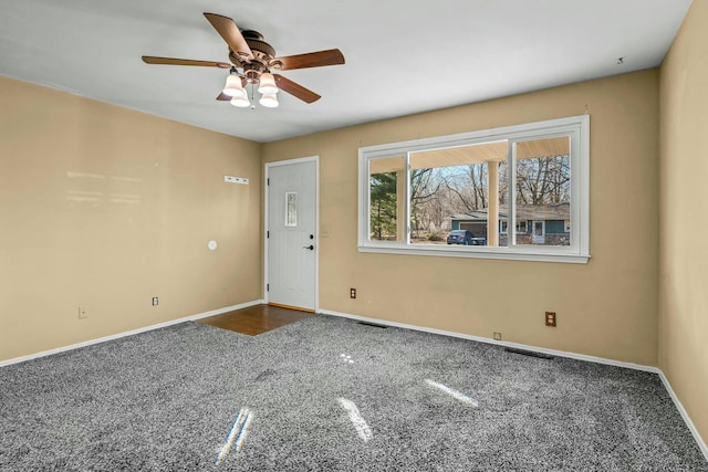 spare room featuring ceiling fan and dark colored carpet