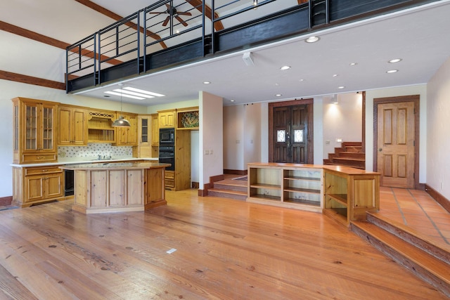 kitchen with light hardwood / wood-style flooring, ceiling fan, a center island, black appliances, and decorative backsplash