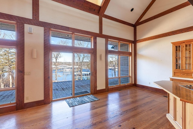 entryway featuring beam ceiling, wood-type flooring, and high vaulted ceiling