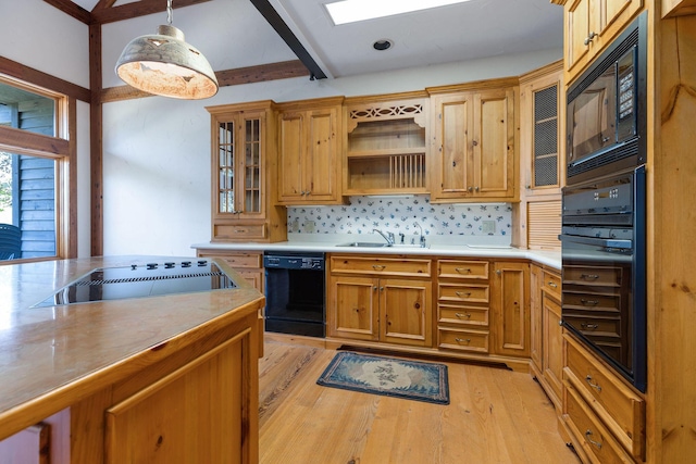 kitchen with sink, tasteful backsplash, light hardwood / wood-style flooring, hanging light fixtures, and black appliances