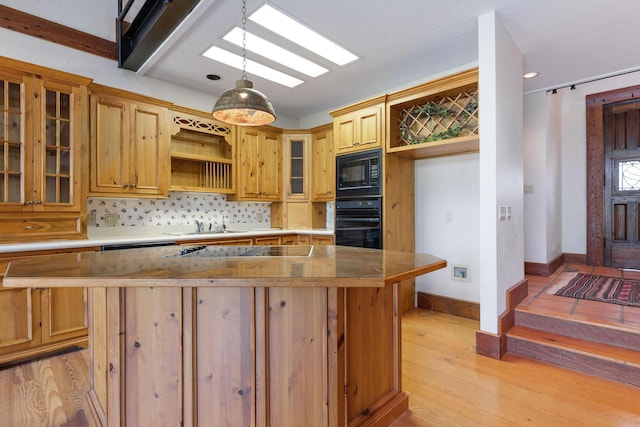 kitchen with backsplash, light wood-type flooring, hanging light fixtures, and black appliances