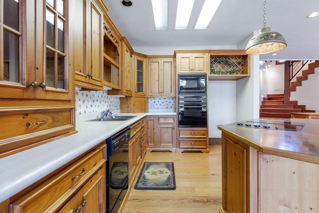 kitchen with sink, black appliances, light hardwood / wood-style flooring, pendant lighting, and backsplash