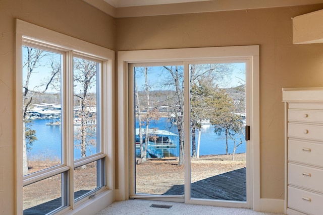 doorway to outside featuring a water view and carpet floors