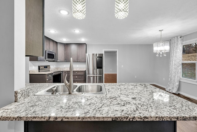 1989 Crawford St, West Plains, MO 65775 - kitchen featuring appliances with stainless steel finishes, dark brown cabinetry, a notable chandelier, a textured ceiling, and decorative light fixtures