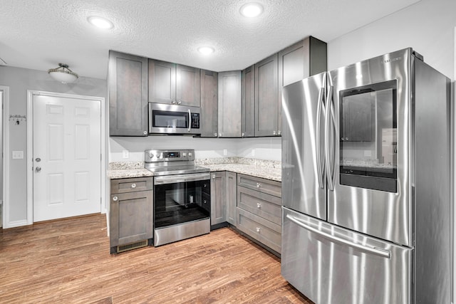 1989 Crawford St, West Plains, MO 65775 - kitchen featuring light stone countertops, light hardwood / wood-style flooring, stainless steel appliances, and a textured ceiling